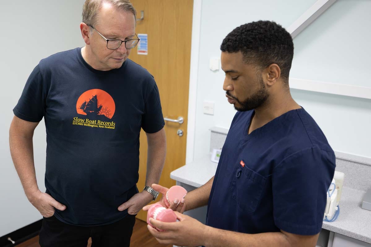 Andrew Stewart, Invisalign dentist at Castle Park Dental Care, explaining treatment to a patient with a dental model